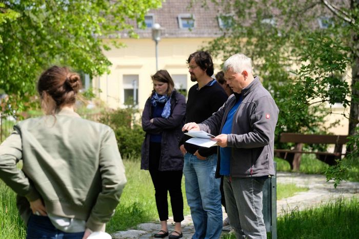 Eine Gruppe von Menschen steht in parkähnlicher Umgebung
