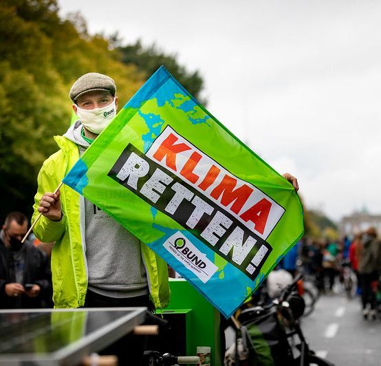 Ein Mann auf einer Demonstration hält ein Banner mit der Aufschrift "Klima retten"